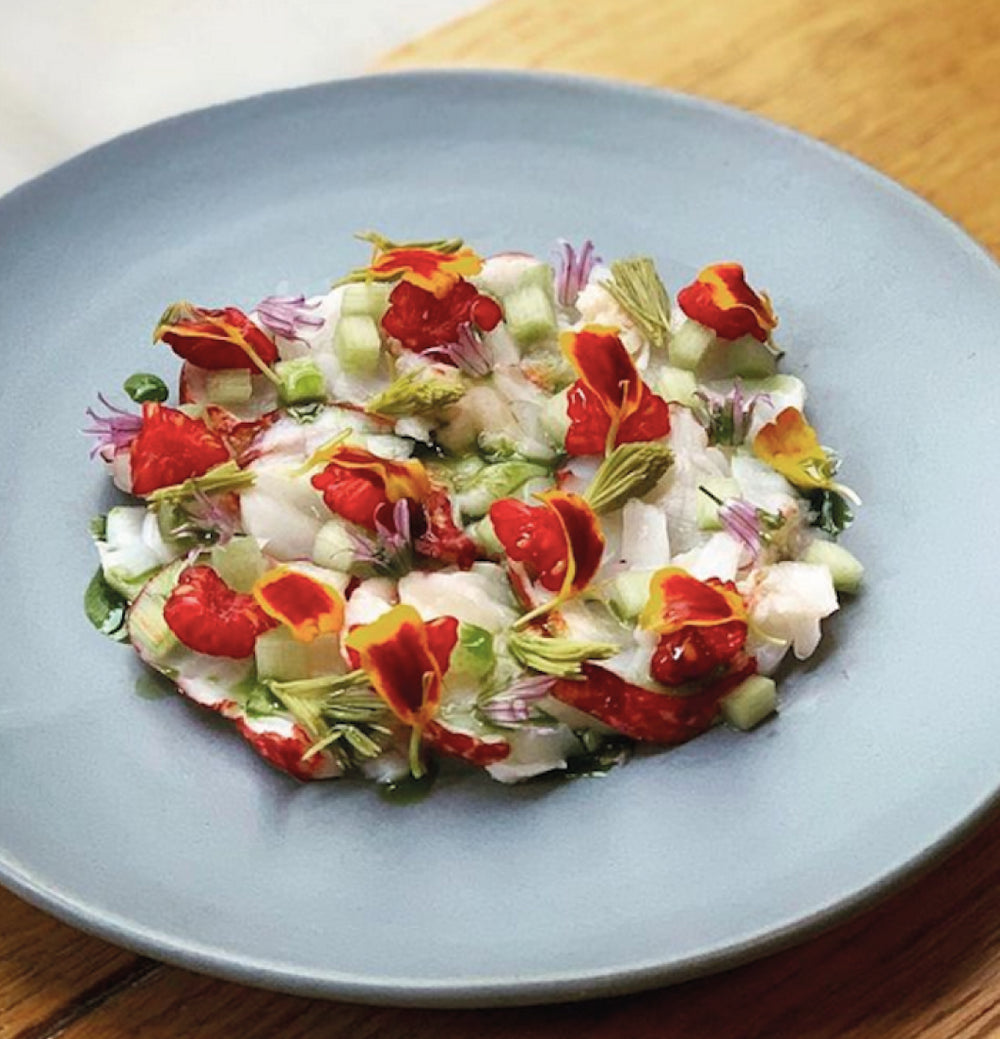 Assiette de crustacés, légumes et fleurs comestibles servie au restaurant Elmer à Paris