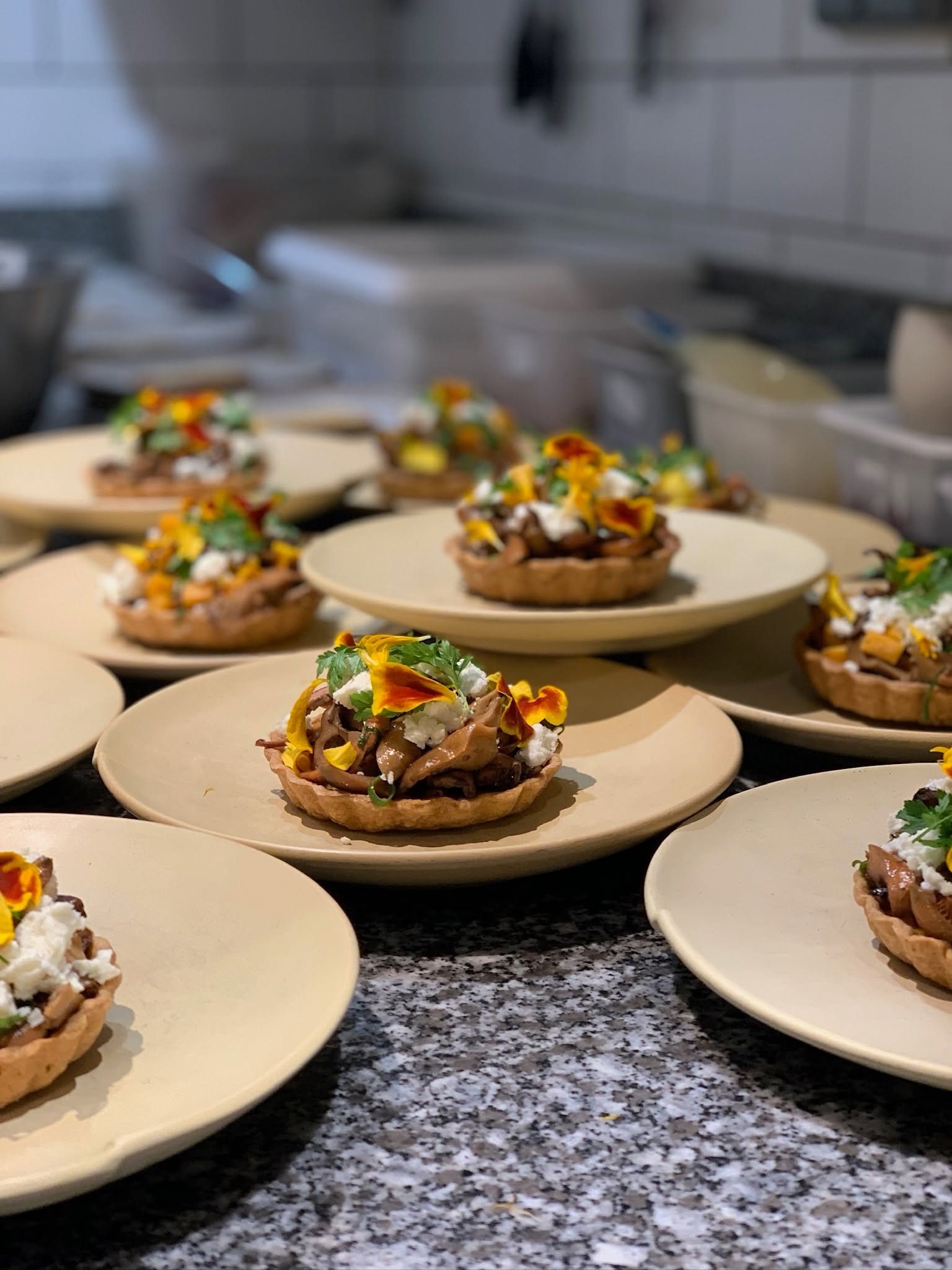 Assiettes en cours de dressage dans la cuisine du restaurant Elmer à Paris