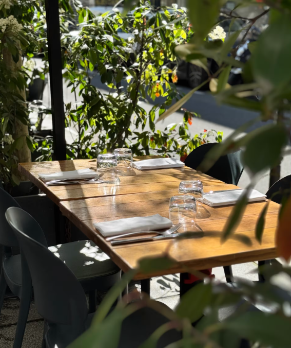Terrasse végétalisée du restaurant Elmer à Paris, avec tables en bois dressées en extérieur